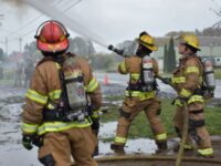 Three fire-men spraying a hose