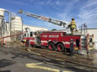 Truck with ladder-boom extended over industrial facility
